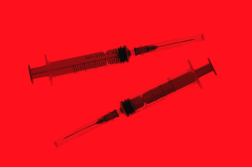 Two plastic disposable syringes with a needles in the protective