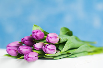 purple tulips sitting on a white crate with a sky blue background