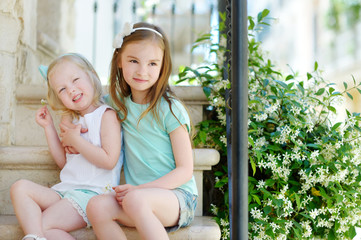 Two adorable little sisters laughing and hugging