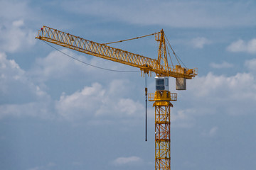 Yellow construction tower crane against sky