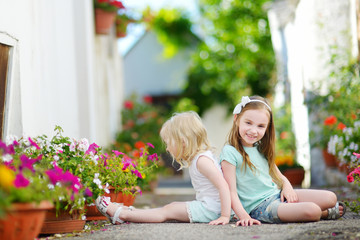 Two adorable little sisters sitting among flowers