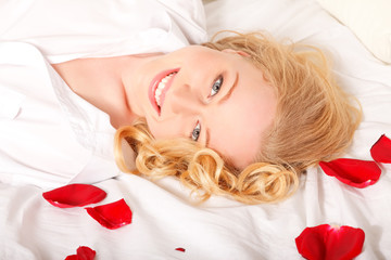 Obraz na płótnie Canvas Happy Woman In Bed With Rose Petals