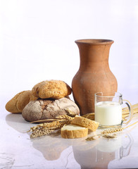 Milk in a transparent mug and fresh bread on a white background