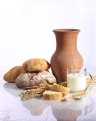 Milk in a transparent mug and fresh bread on a white background