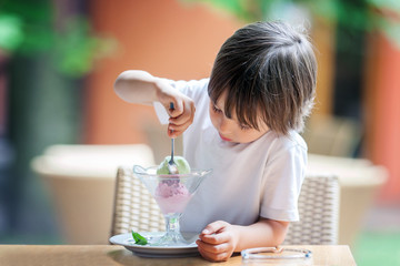 Cute little boy, eating ice cream in a restaurant