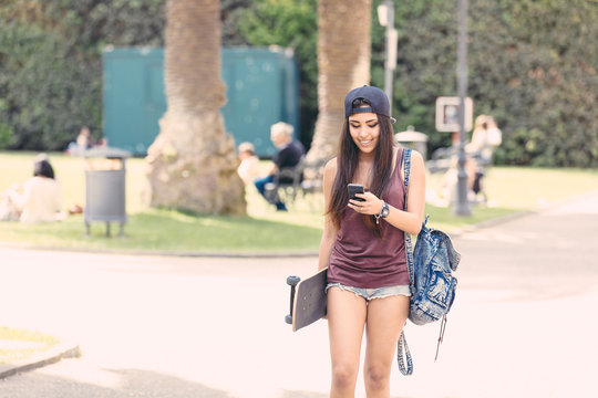 Portrait of a beautiful skater girl looking at smart phone