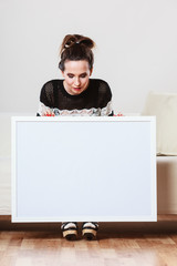 woman on sofa holding blank presentation board.