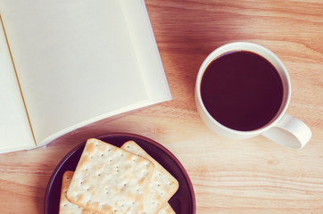 Blank open book with cup of coffee and biscuit on wooden table -