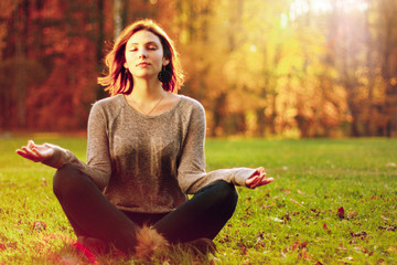 Young attractive female meditate in park.