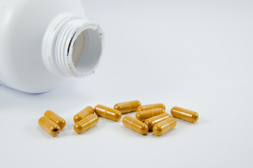 herb capsules from bottle isolated on white background