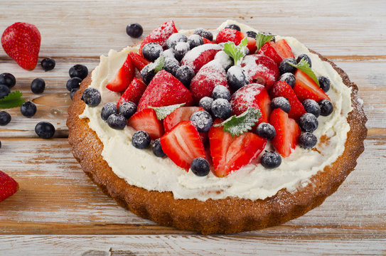 Sweet Cake with fresh berries on  wooden background.
