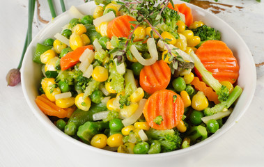 Mixed vegetables with fresh herbs in  white bowl.