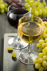 glasses of white and red wine and grapes on a blackboard