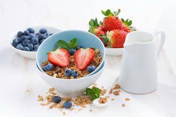 healthy food - granola, fresh berries and milk on white table