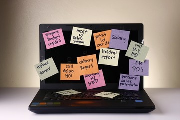 Laptop computer with messages on colorful papers, cellphone, smartphone, notebook, pen, pencil and eyeglasses