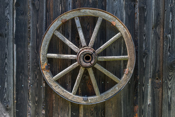 Old wooden carriage wheel hanging on the barn.