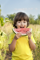 Fototapeta premium happy child eating watermelon in the garden