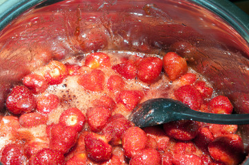 Cooking strawberry jam in a silver pot on the stove