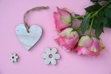 pink painted wooden background with bunch of pink roses and a heart shape photo frame decorated with white wash flowers