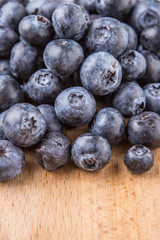 Blueberry fruits in a white bowl on wooden board background