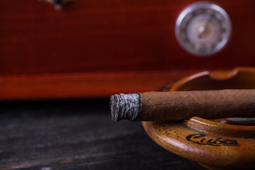 Cuban cigar in  ashtray and wooden humidor