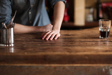 Fototapeta na wymiar Barman leaning on wooden bar counter