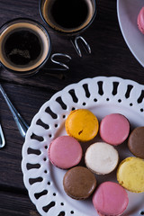 Fresh vibrant macaroons on plate with coffee
