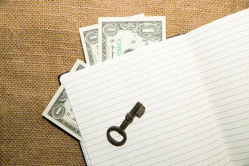 Opened notebook, key and money on the old tissue