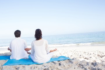 Happy couple doing yoga beside the water
