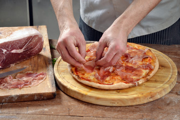 Cocinero preparando pizza de jamon,prosciutto.