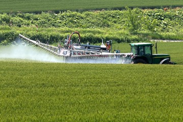Obraz premium 美瑛の丘ブームスプレーヤによる畑への薬液散布作業