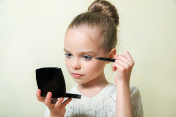 Fashion little girl applying make up. Mascara, eye shadow, lip g