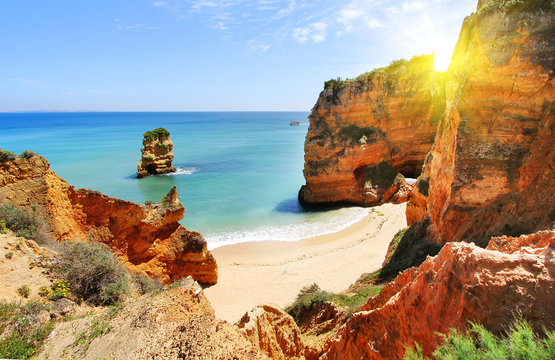 Rocky beach at sunset, Lagos, Portugal. Counter light. Travel and business background