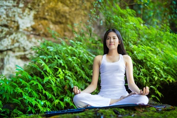 Asian woman doing yoga in forest