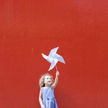 Smiling girl holding a pinwheel in the air making a Hong Kong flag
