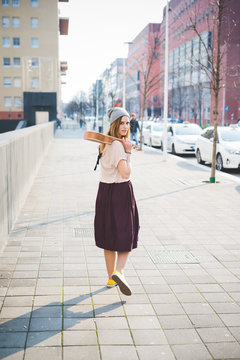 Portrait of young woman walking with ukulele on street