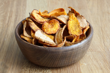 Detail of fried carrot and parsnip chips in rustic wood bowl.