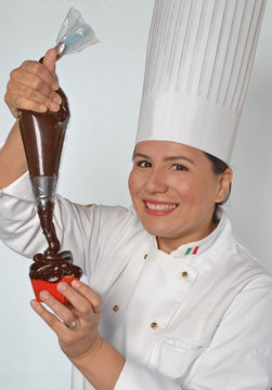 Cocinera preparando pastel,tortitas de crema de chocolate y fresa