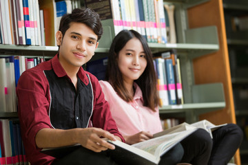 Asian male and female students reading at library