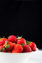 fresh strawberry in white plate on black background