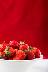 fresh strawberry in white plate on red background