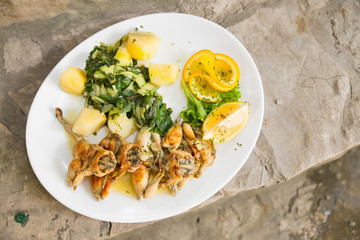 Lunch, frogs legs/Serving plate with crisp frog legs with potatoes and chard