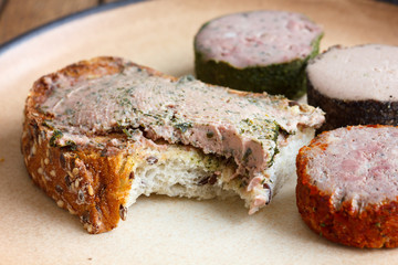 Whole grain toast spread with pate, bite missing.