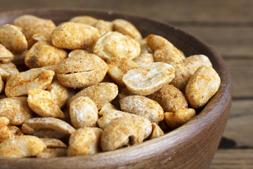 Spicy dry roasted peanuts in rustic wood bowl.