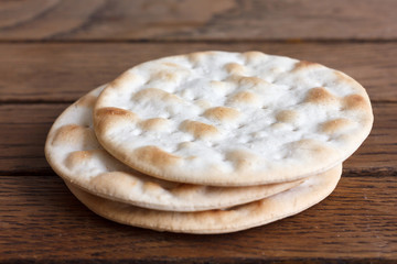 Three water biscuits on rustic dark wood.