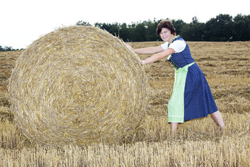 Naklejka na ściany i meble Woman rolling straw bale