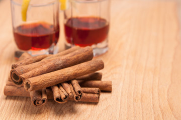 glass heating red liqueur with cinnamon sticks on table