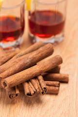 glass heating red liqueur with cinnamon sticks on table