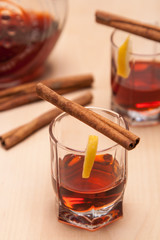 glass heating red liqueur with cinnamon sticks on table