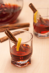 glass heating red liqueur with cinnamon sticks on table